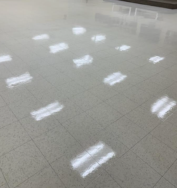 Shiny, light-colored, tiled floor with reflections of overhead lights.