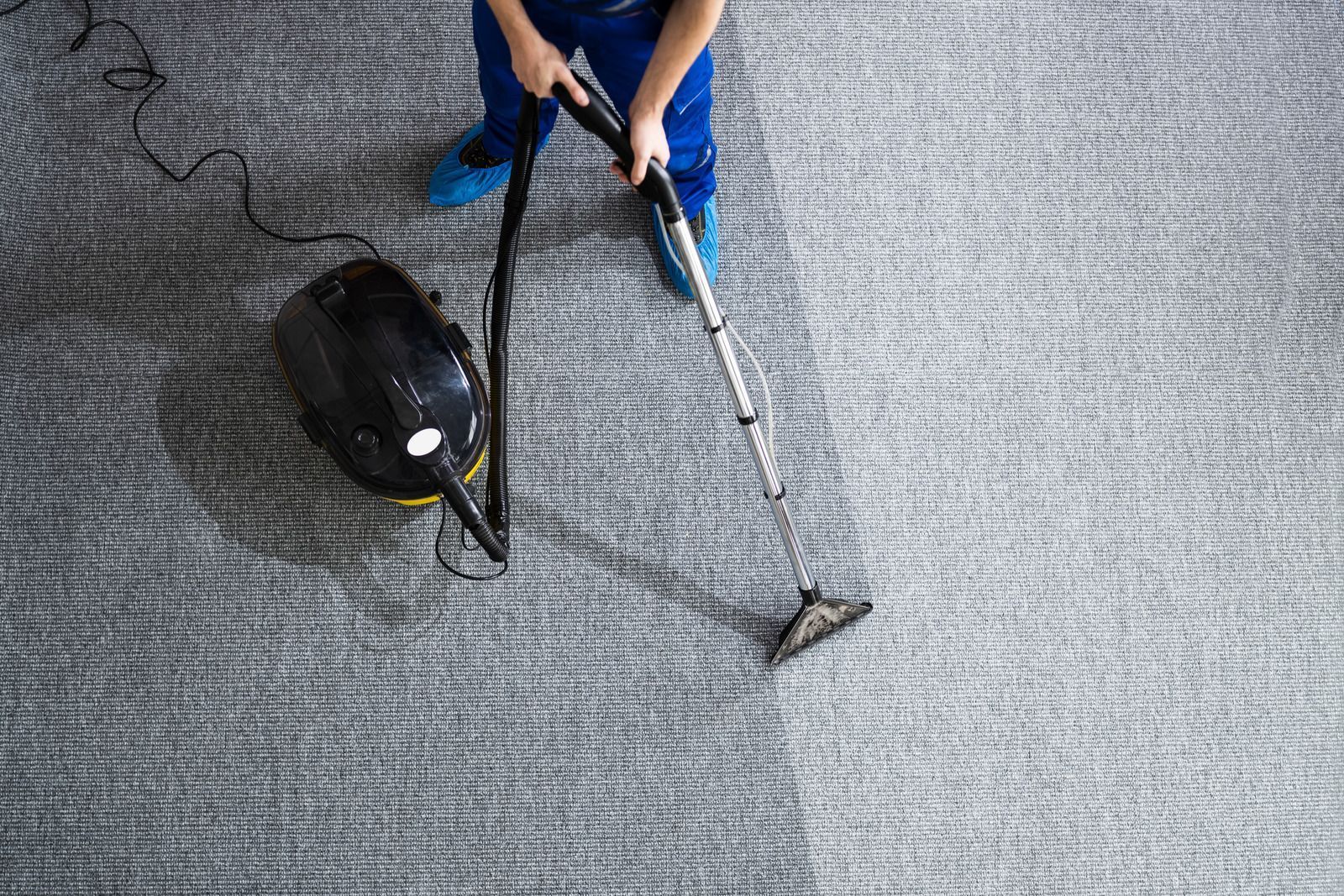 Person using blue-handled tools on gray carpet next to a black mouse and cable.