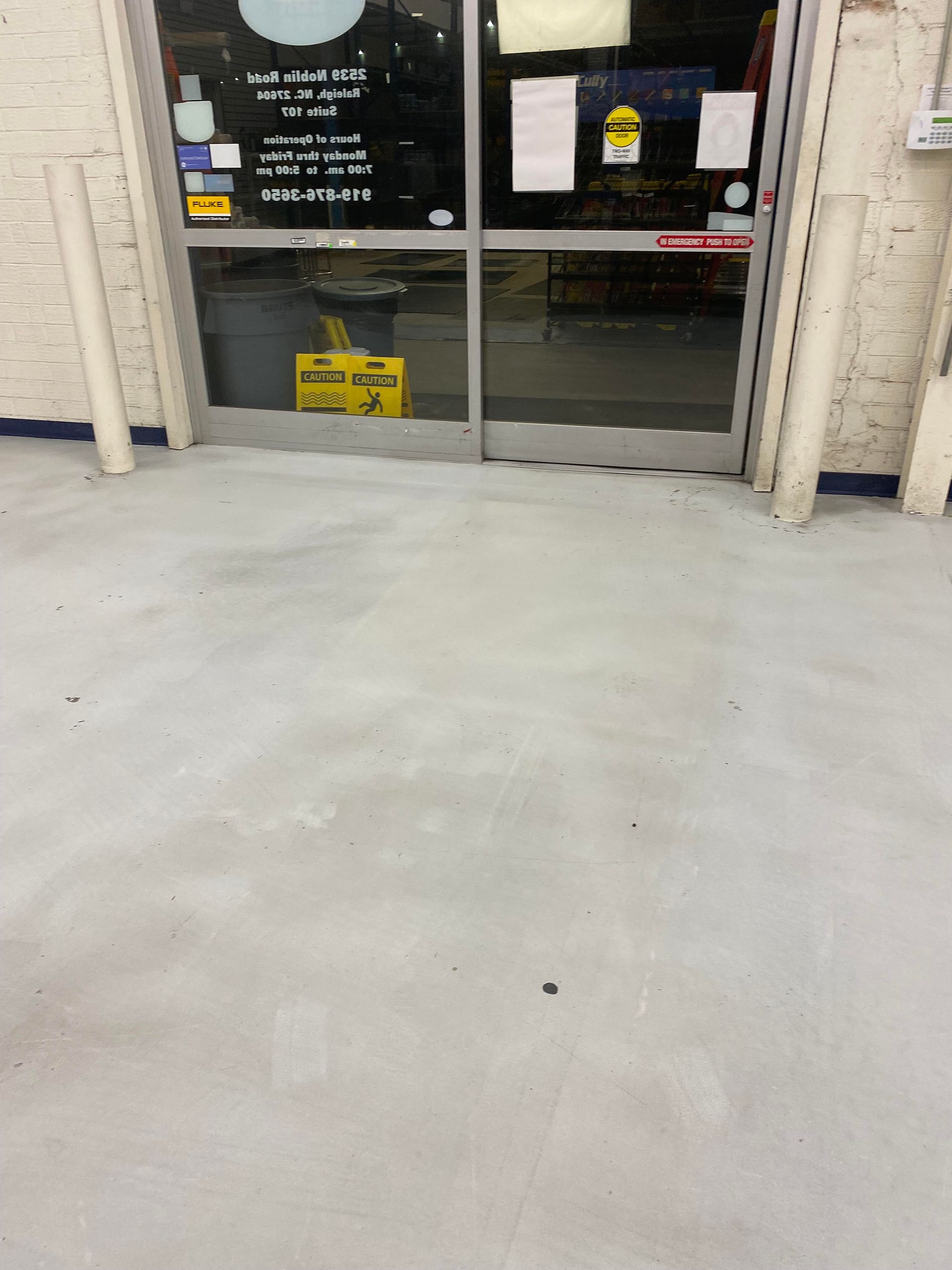 Entrance to a store with glass doors, light gray floor, and cylindrical pillars on either side.