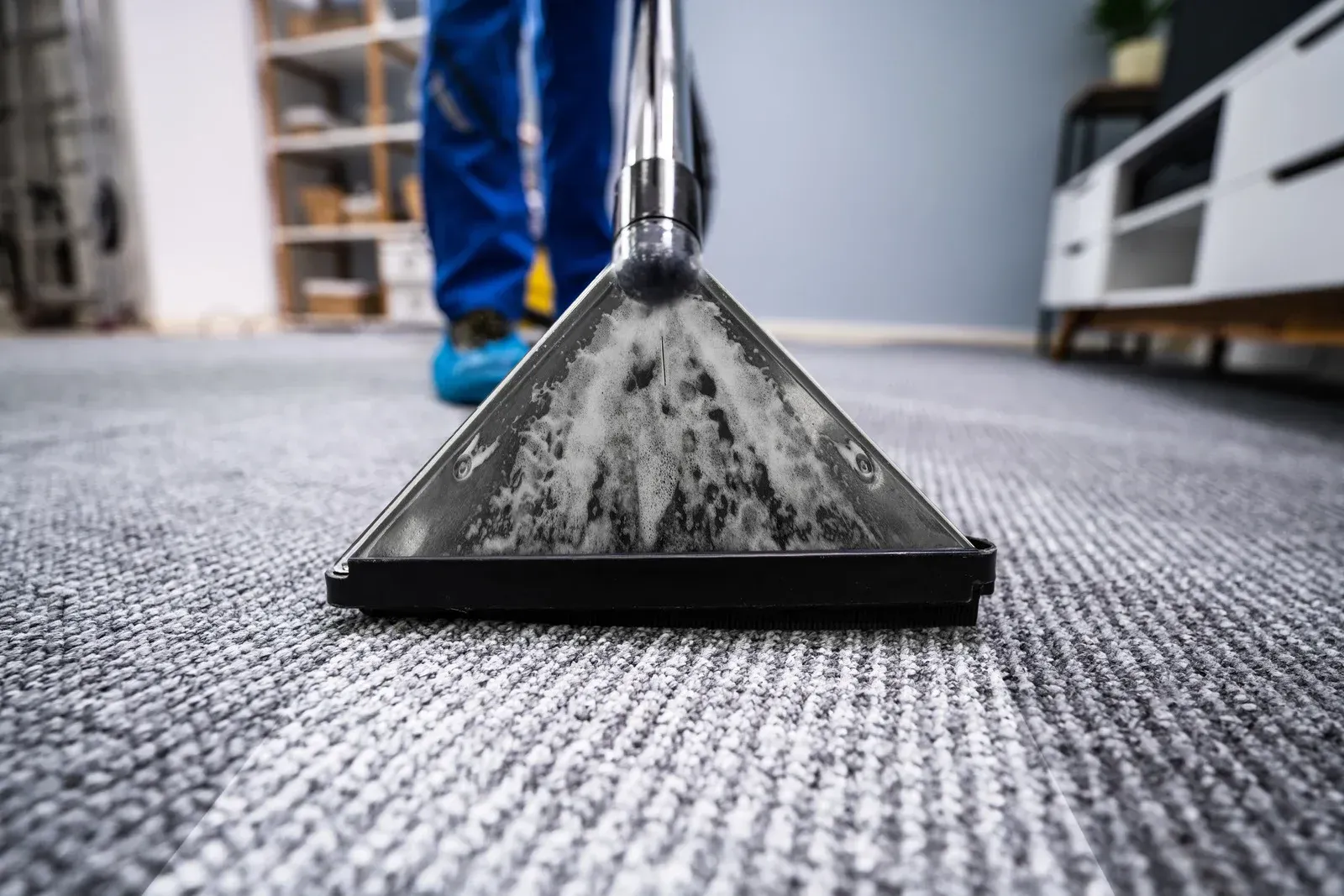 Carpet cleaning nozzle on gray carpet with a person in the background