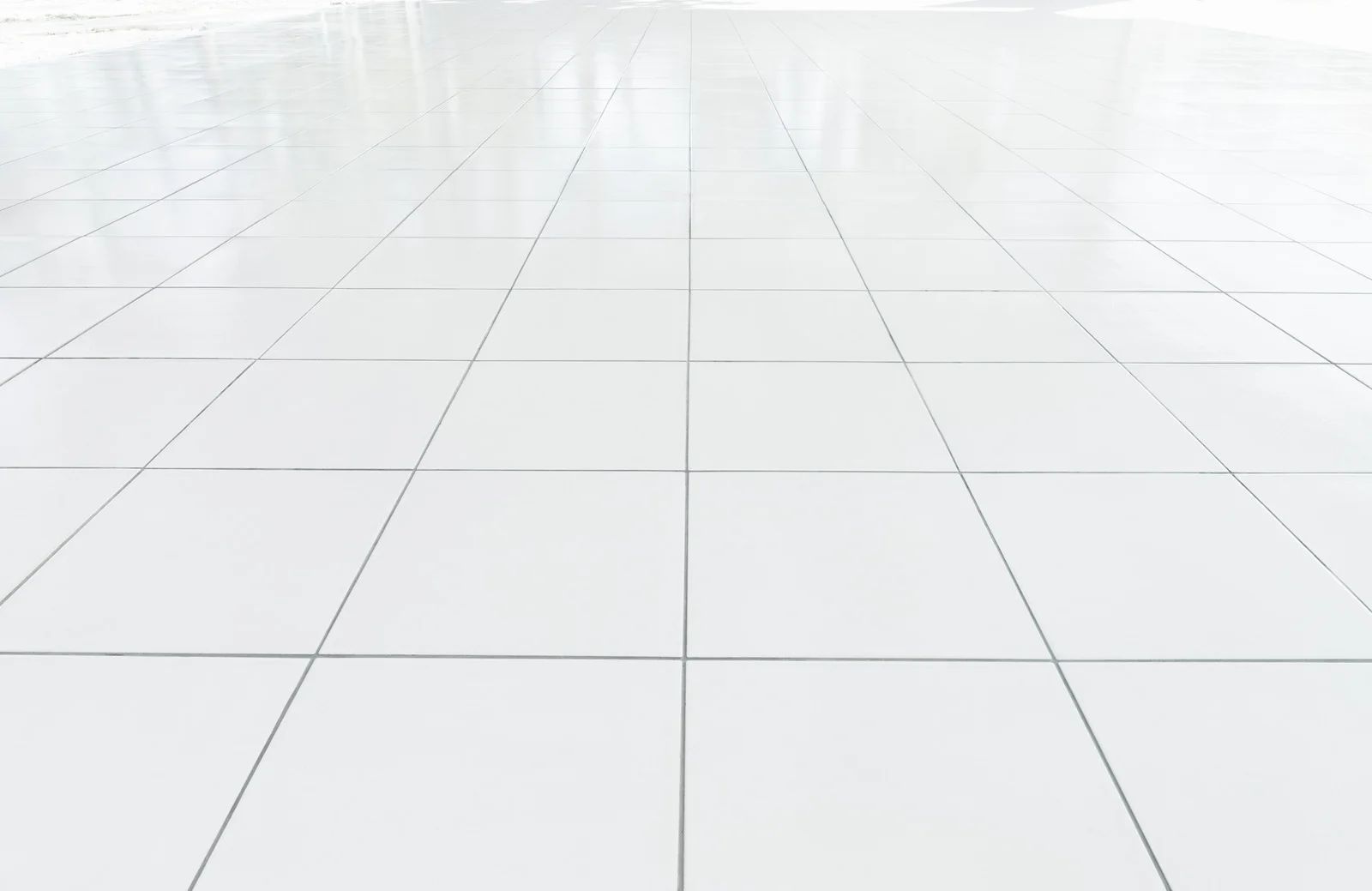 Empty white tiled floor receding into a bright, minimal background