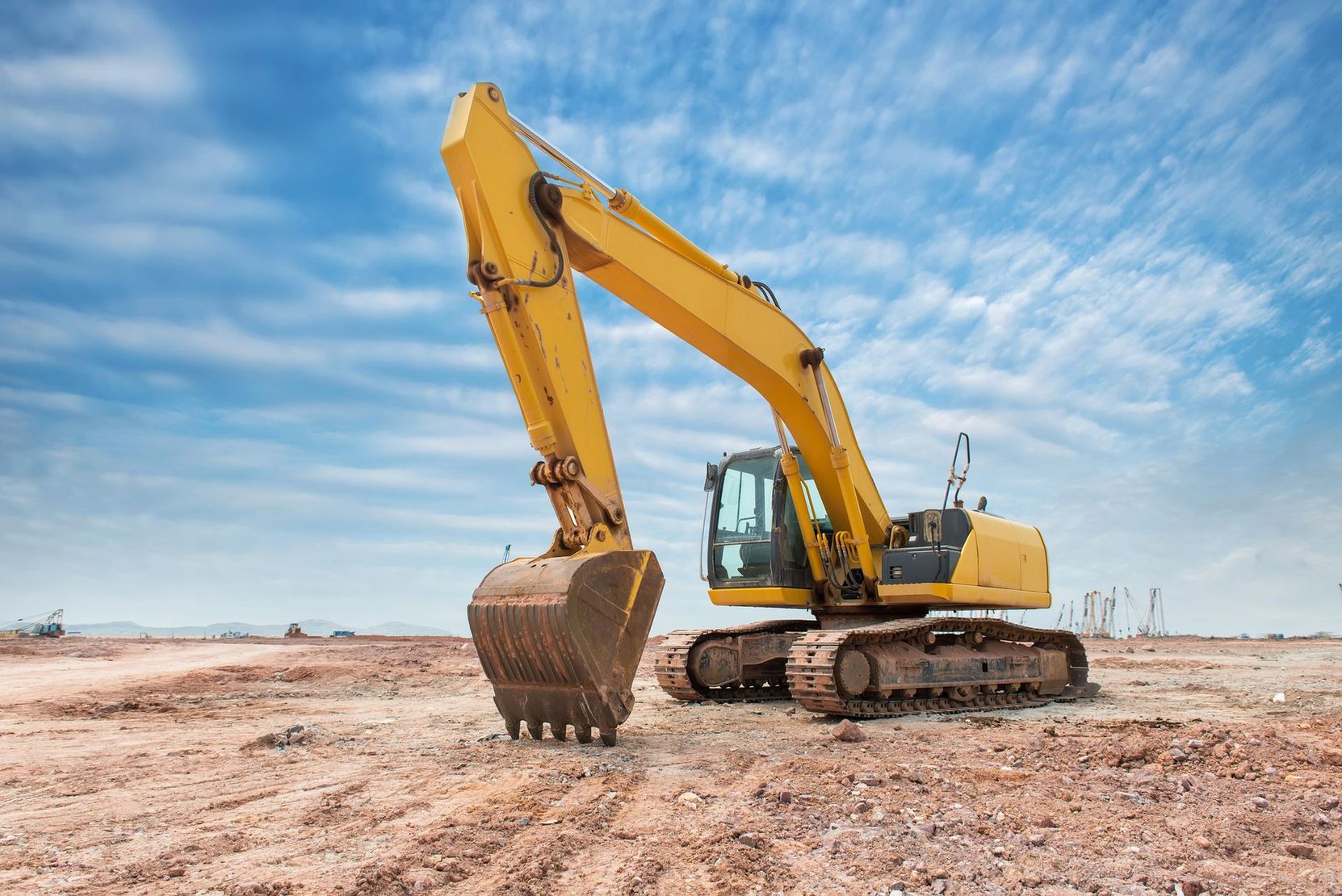 Escavatore giallo in un cantiere sotto un cielo azzurro
