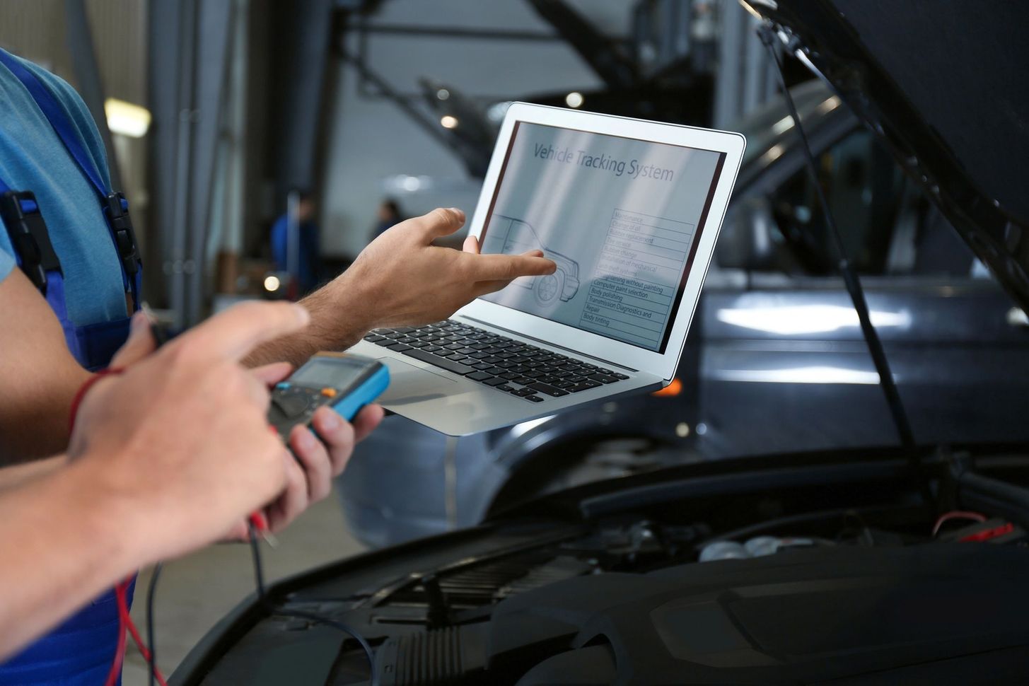 Meccanico che usa un laptop per diagnosticare il motore di un’auto in un’officina di riparazione
