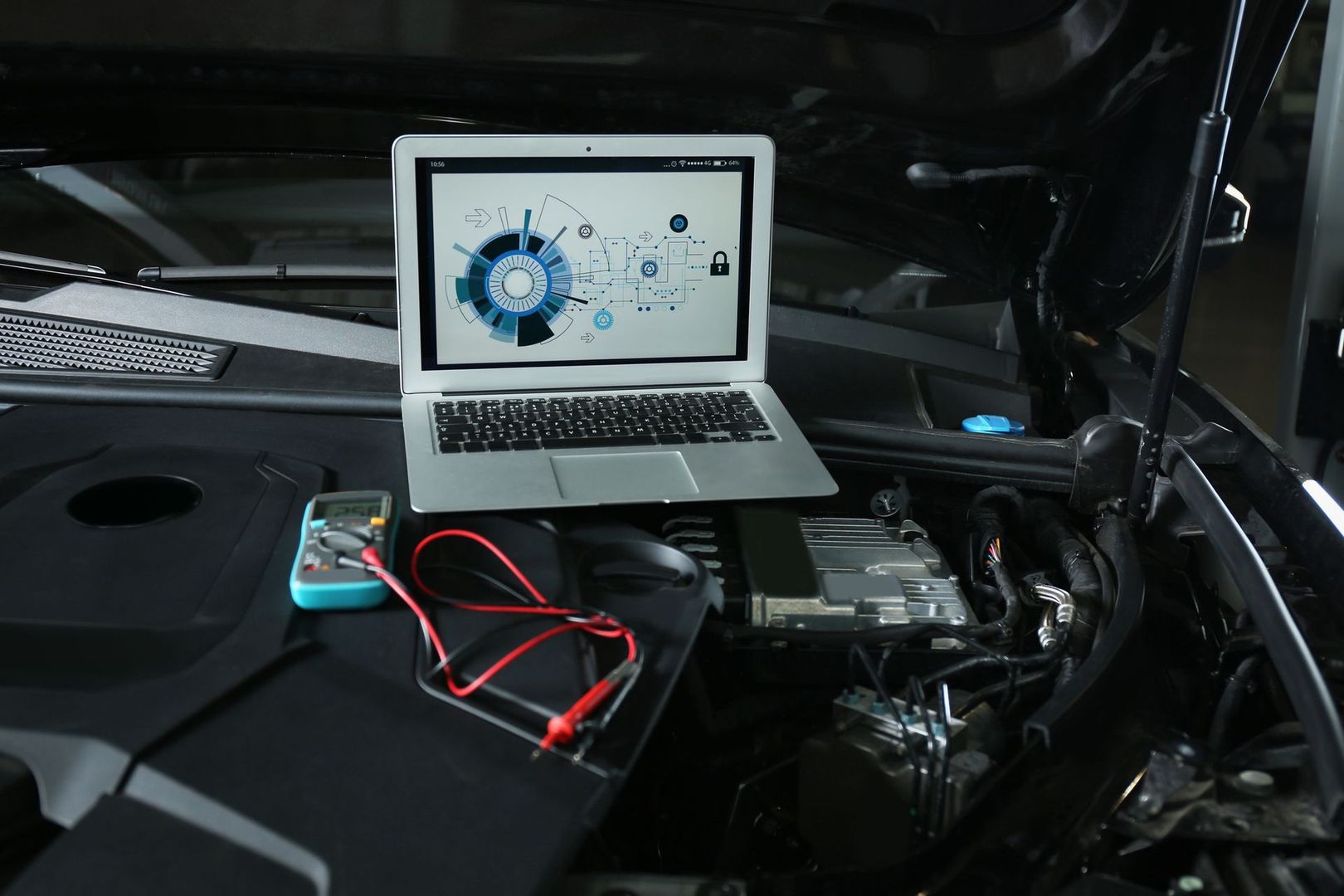 Laptop e cavi nel vano motore di un'auto, con apparecchiatura diagnostica collegata per le riparazioni