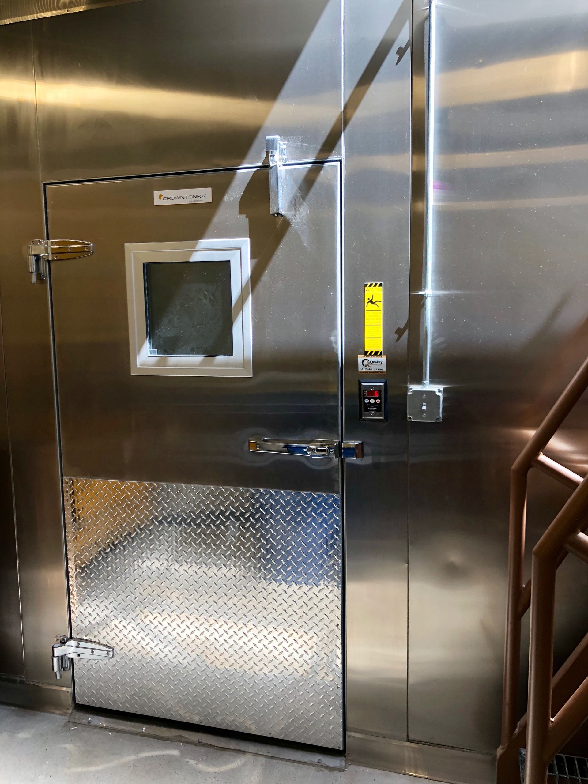 A stainless steel door in a room with stairs