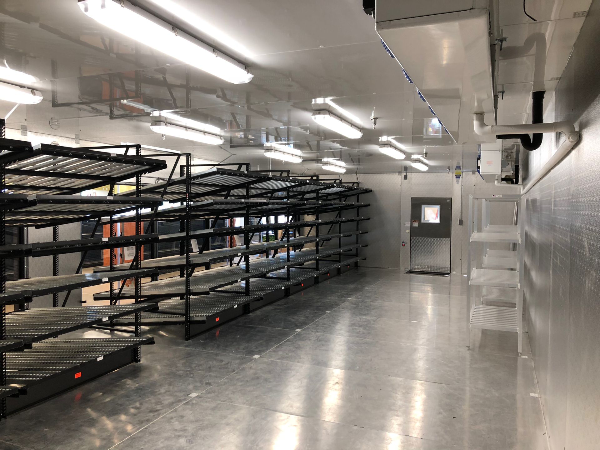 A large empty room with lots of shelves and lights.