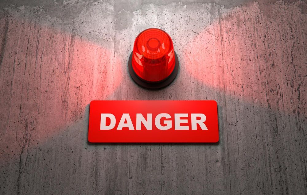 Red warning light above a red “DANGER” sign on a concrete wall
