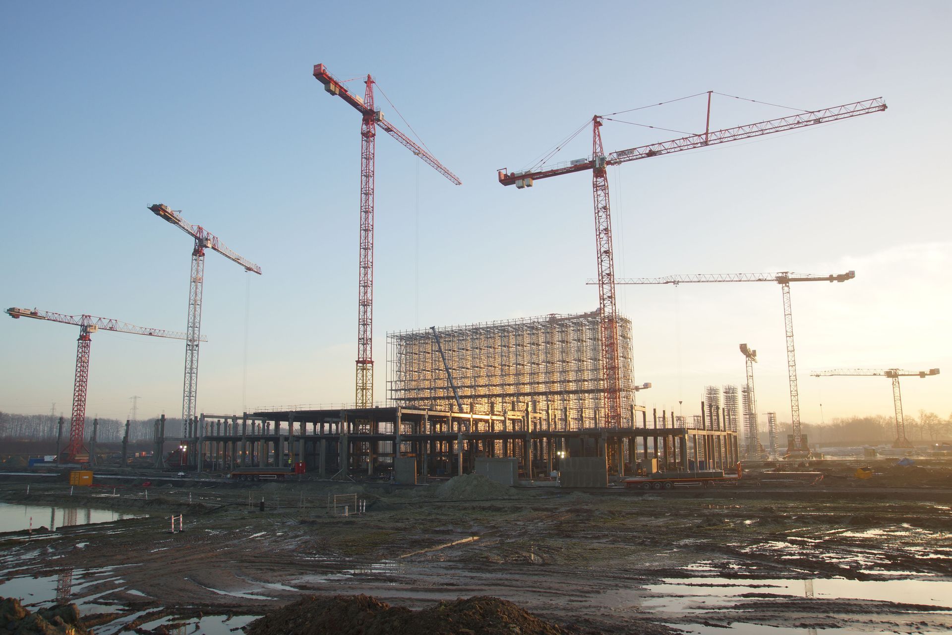 Tower cranes over a commercial building under construction at sunrise