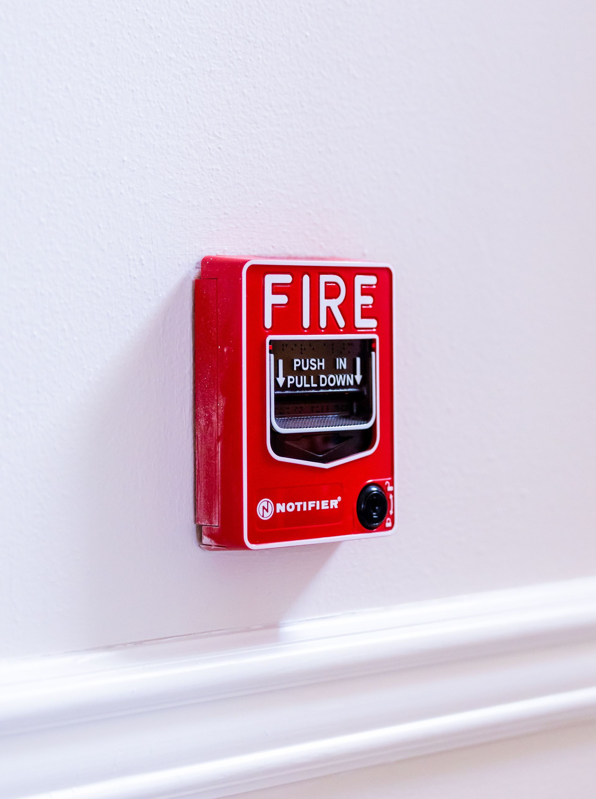 Red fire alarm pull station mounted on a commercial wall