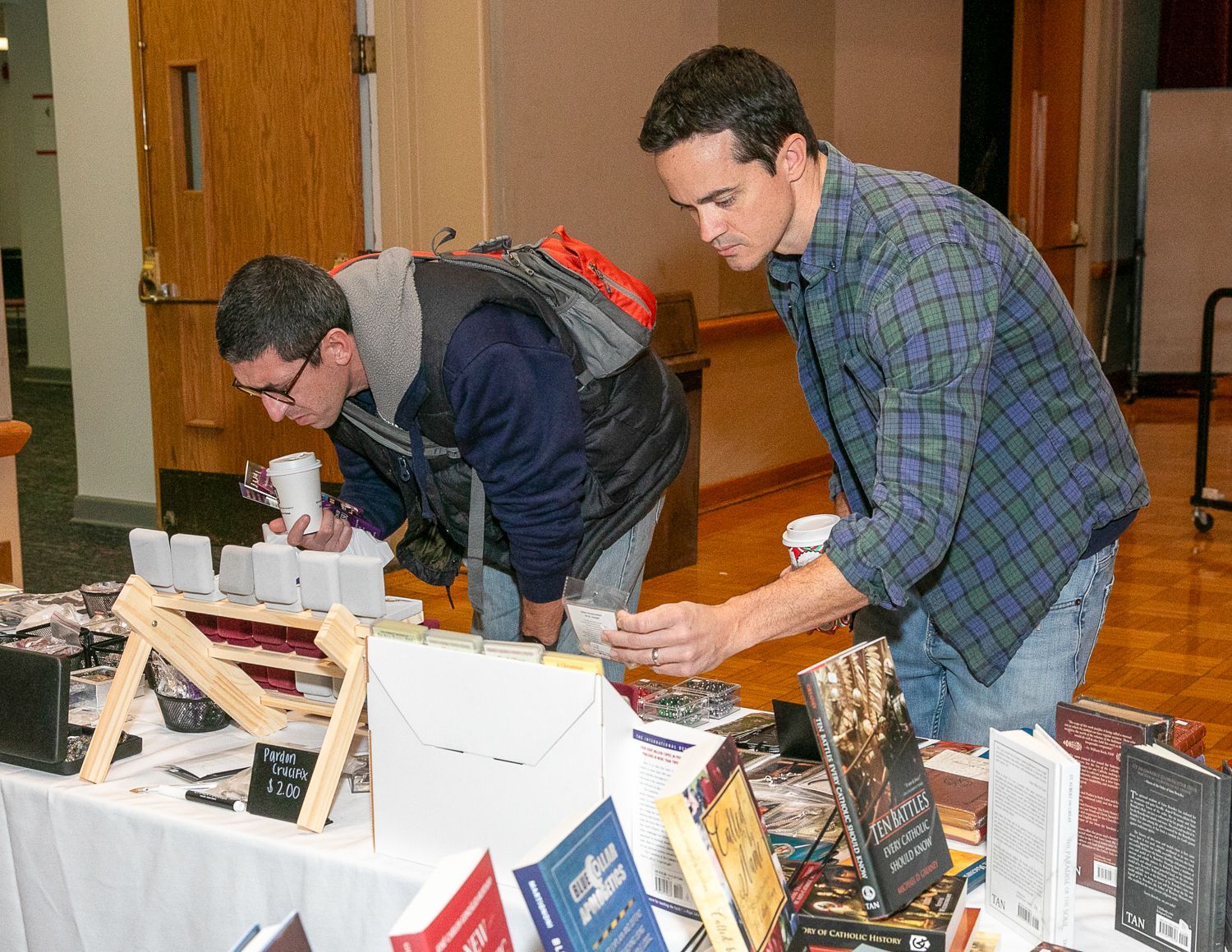 Two people browse books at a display table in a bookstore or library.