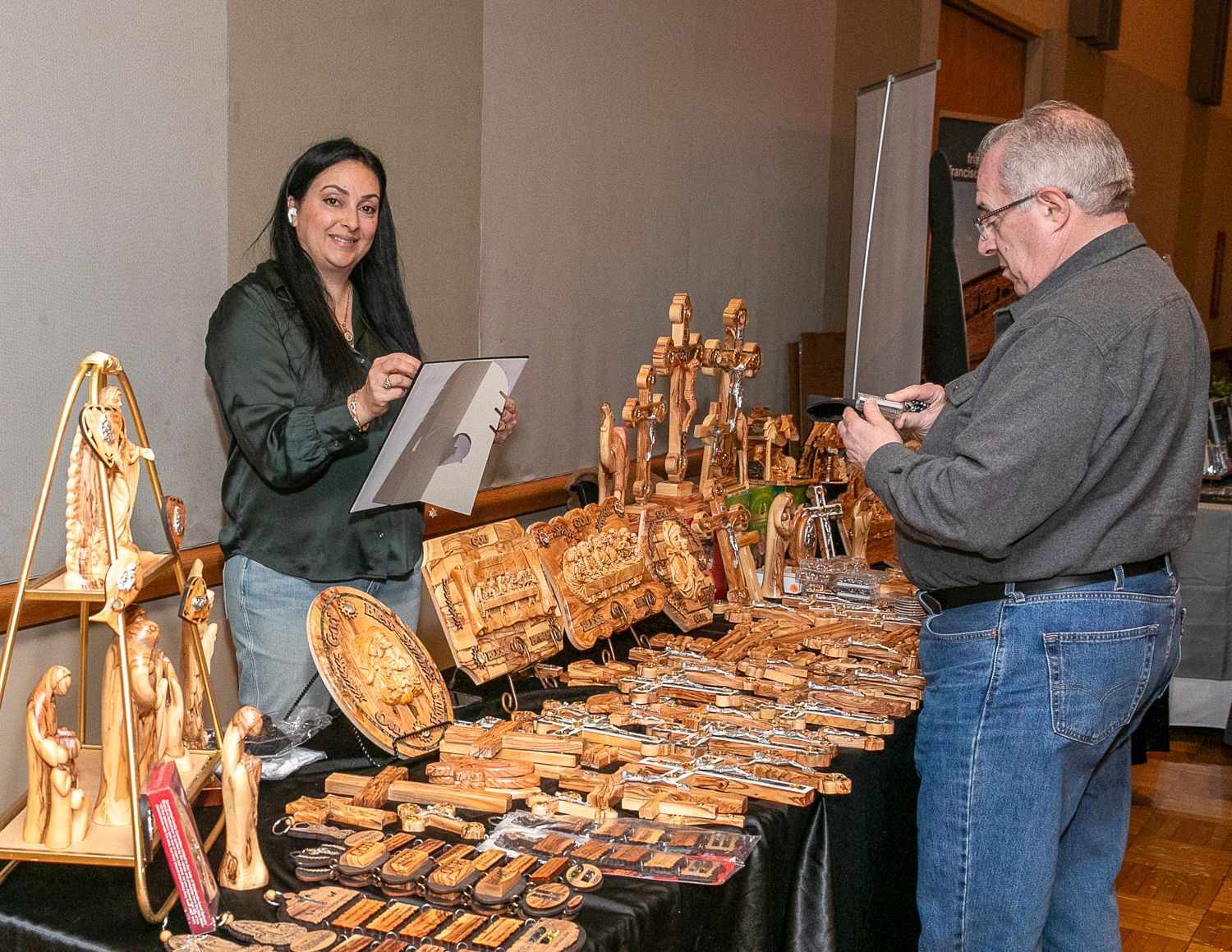 Two people at a jewelry display table, one showing items and the other examining them.