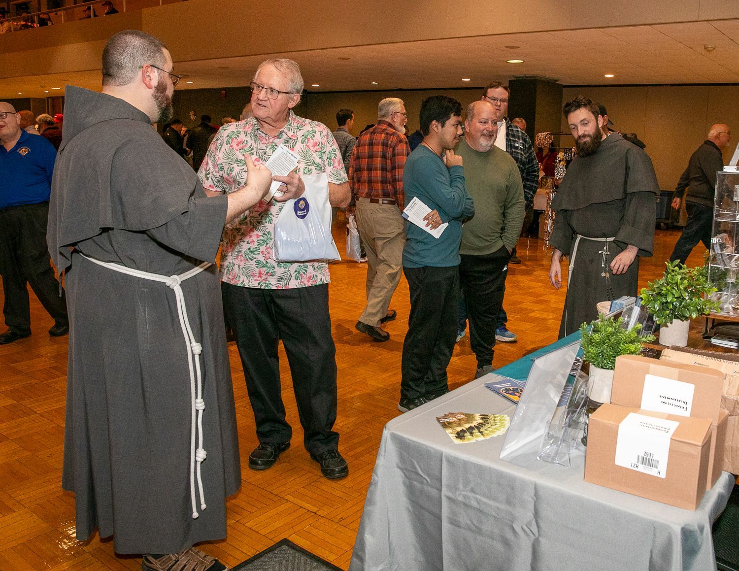People chatting at a conference table with brochures and boxes in a lobby area