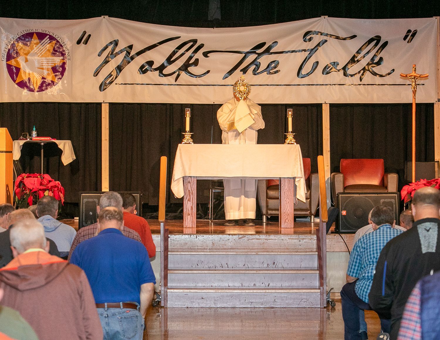 People standing in a church facing an altar with a priest and a “Walk the Walk” banner overhead
