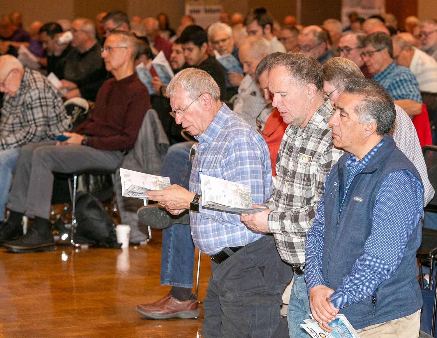 Audience seated in a hall, reading programs and listening attentively.