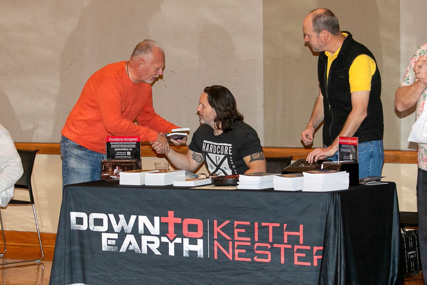 Signing booth with people at a table, and a banner reading “Downtown Earth Keith Nester”