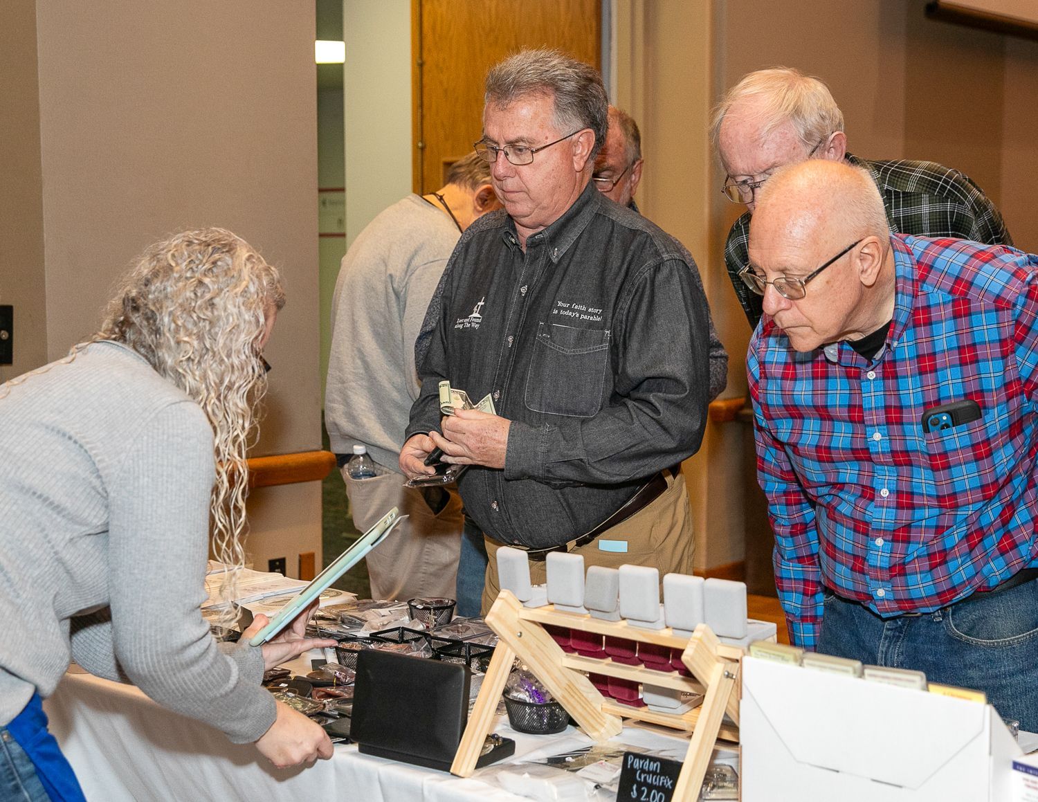 People gathered around a table examining a display of objects and models at an indoor event