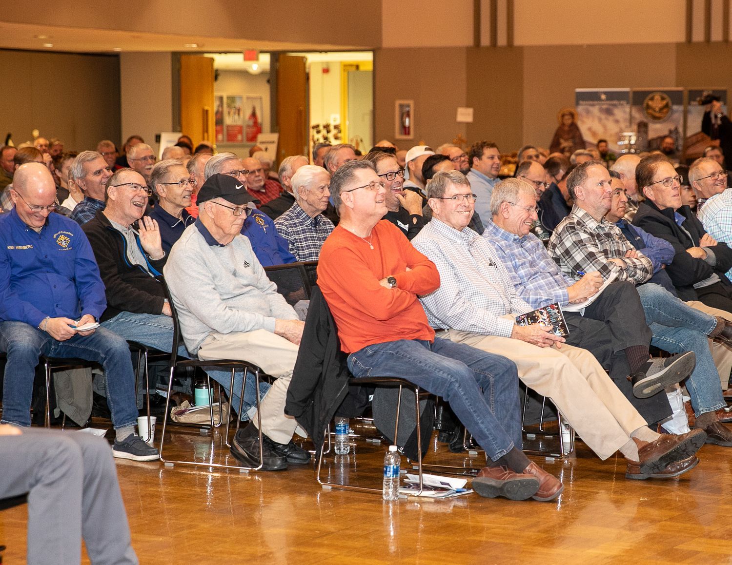 Audience seated in a conference hall, listening attentively during a presentation