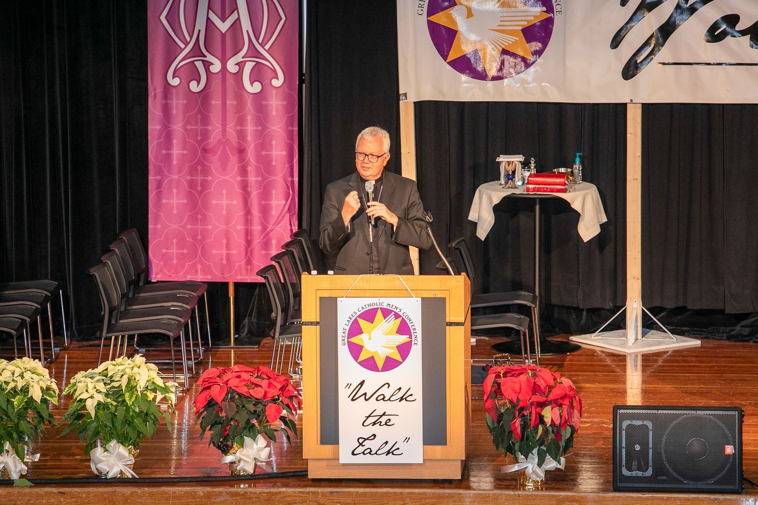 Speaker at podium on stage with floral decorations and banners