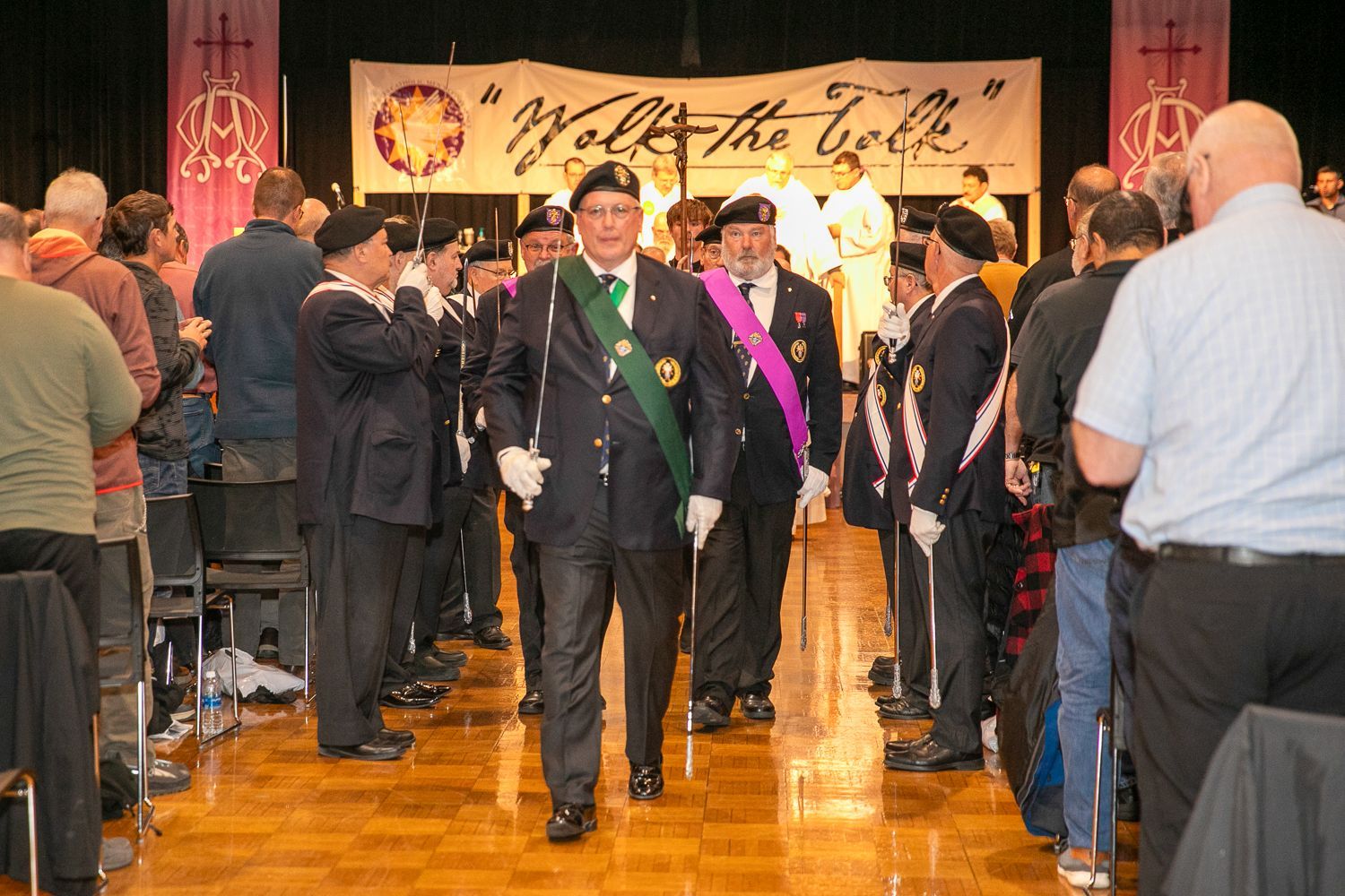 Knights of Columbus in formal attire walk down a polished hallway at an event under a “Walk for Life” banner.