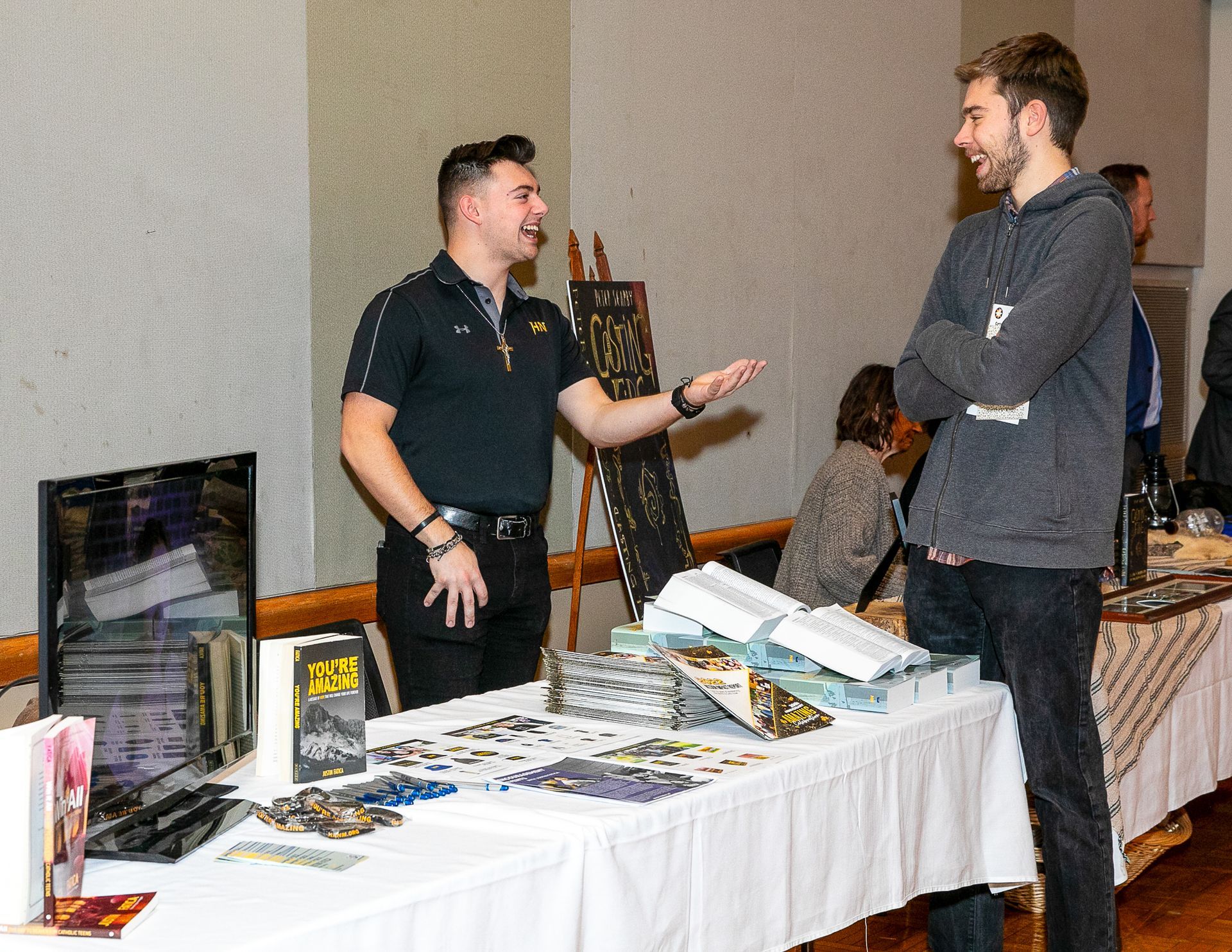 Two people talking at a trade show booth with a table of brochures and displays