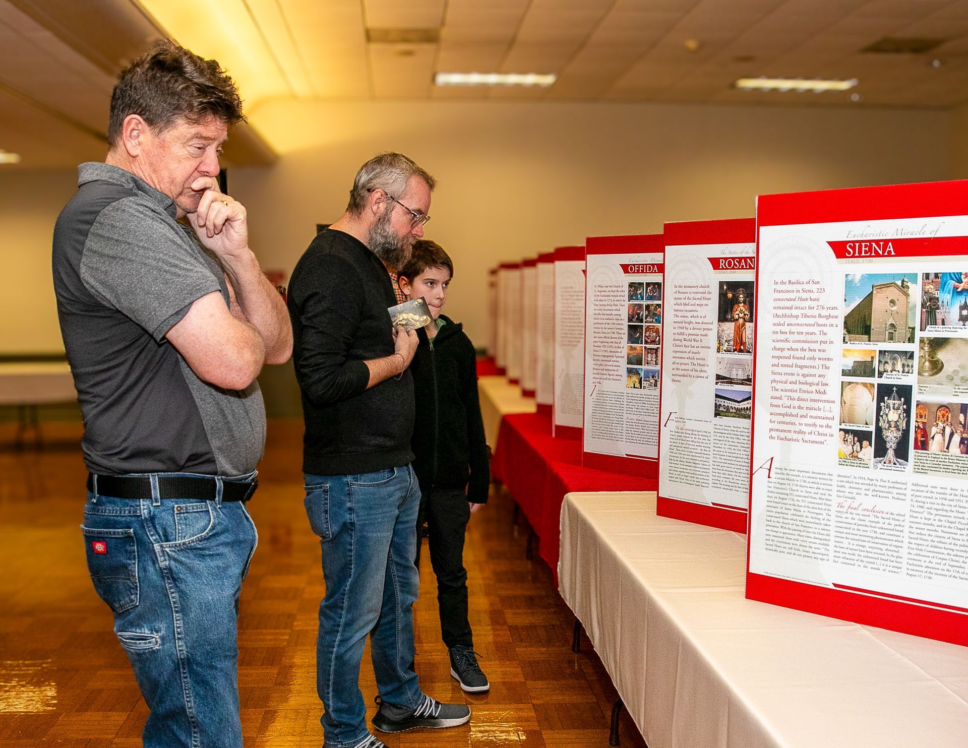 People viewing poster boards at an indoor exhibit display.