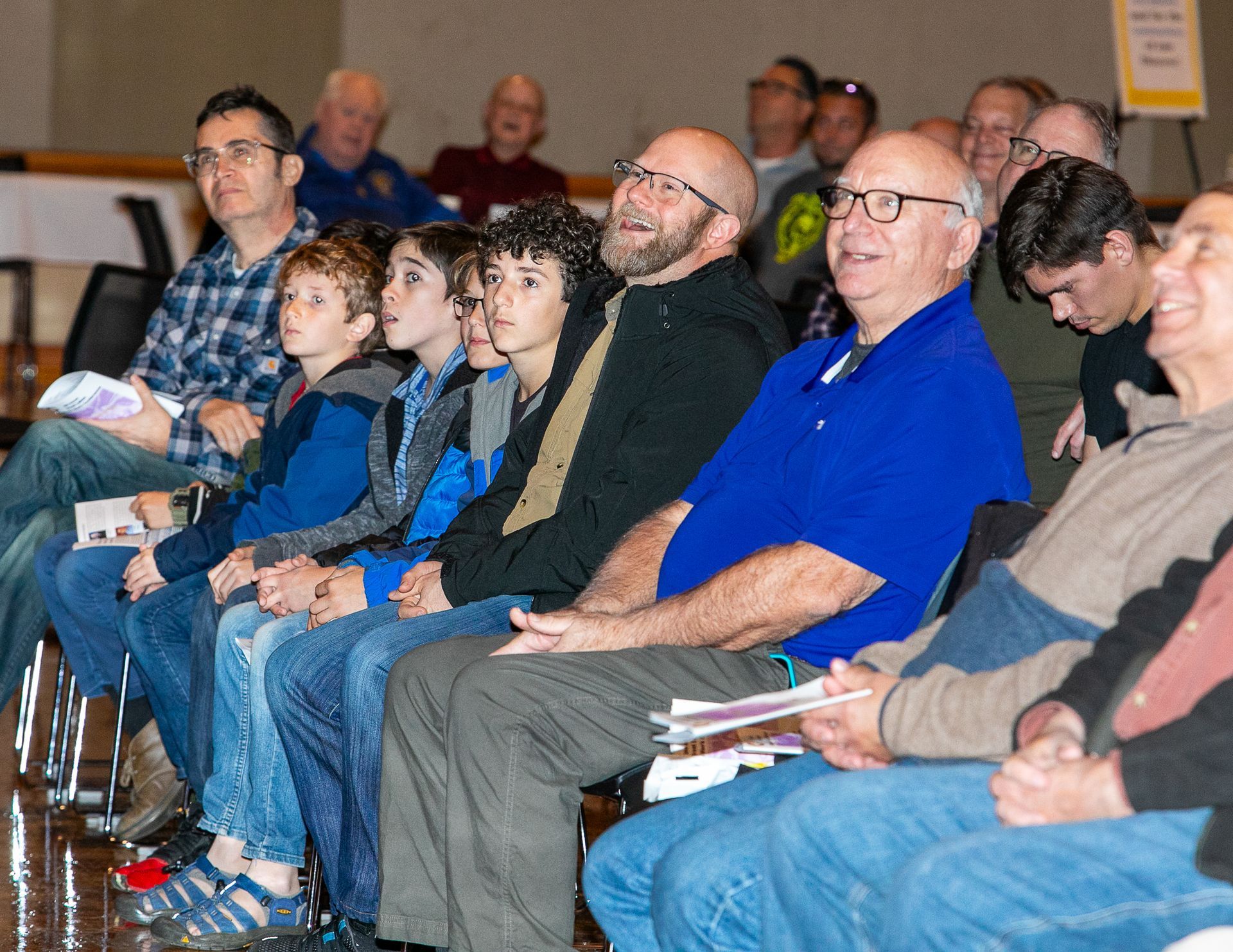 Audience seated in a row, listening attentively at an indoor event