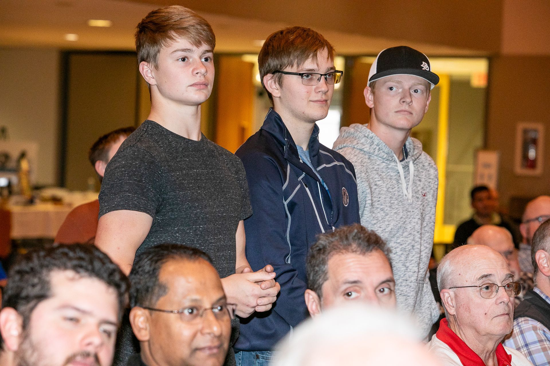 Audience members standing in a warmly lit room during a gathering