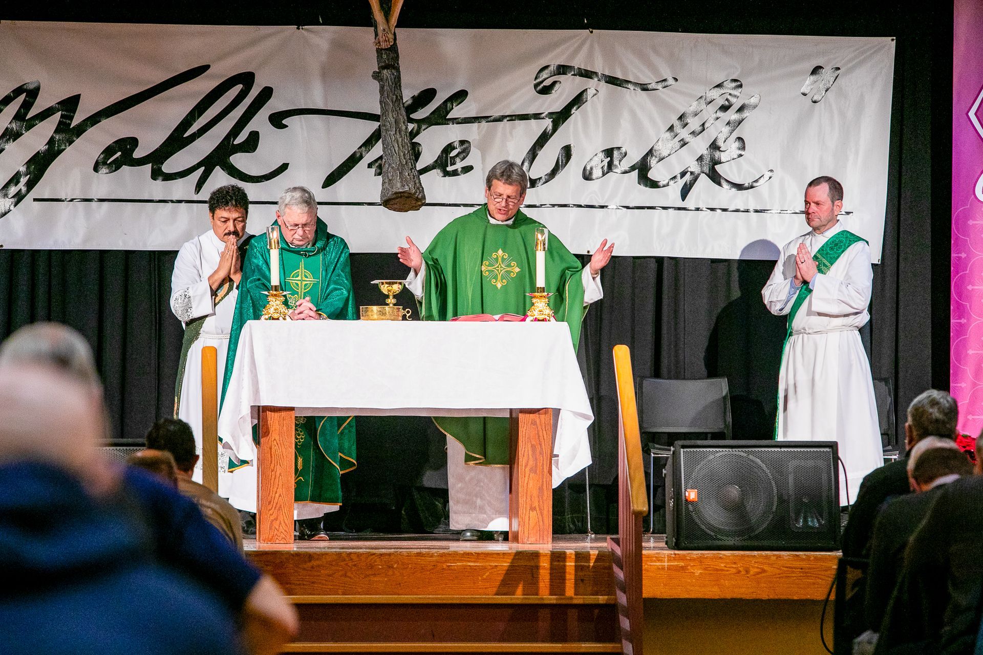 Priests in green vestments stand at a church altar during a service