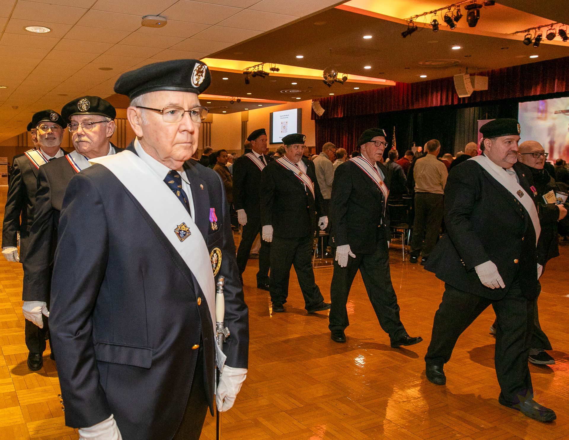 Knights of Columbus walking through a warmly lit hall at a Catholic men's conference.