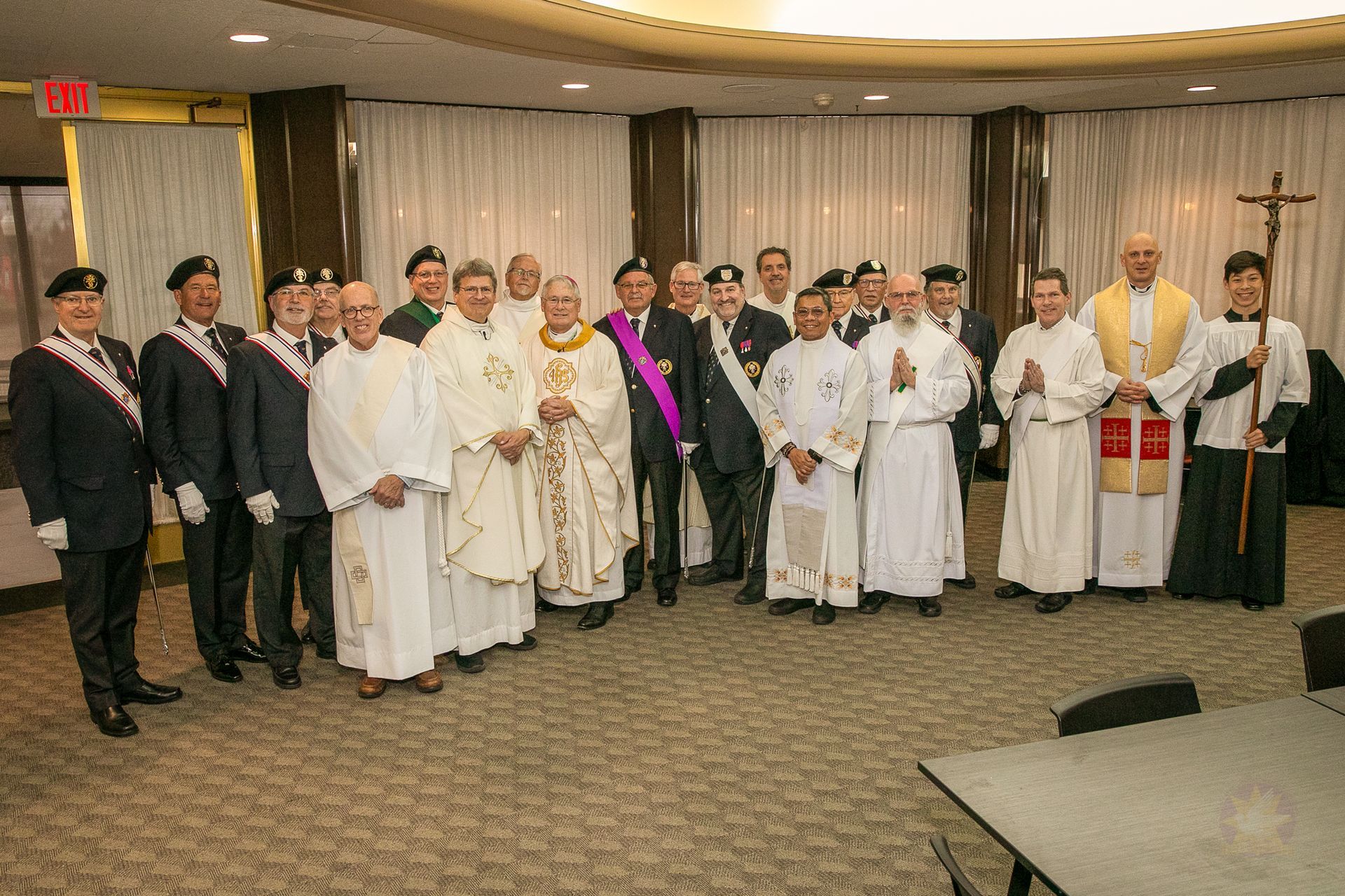 Group of people in formal attire standing at a Catholic men's conference, posing for a photo.