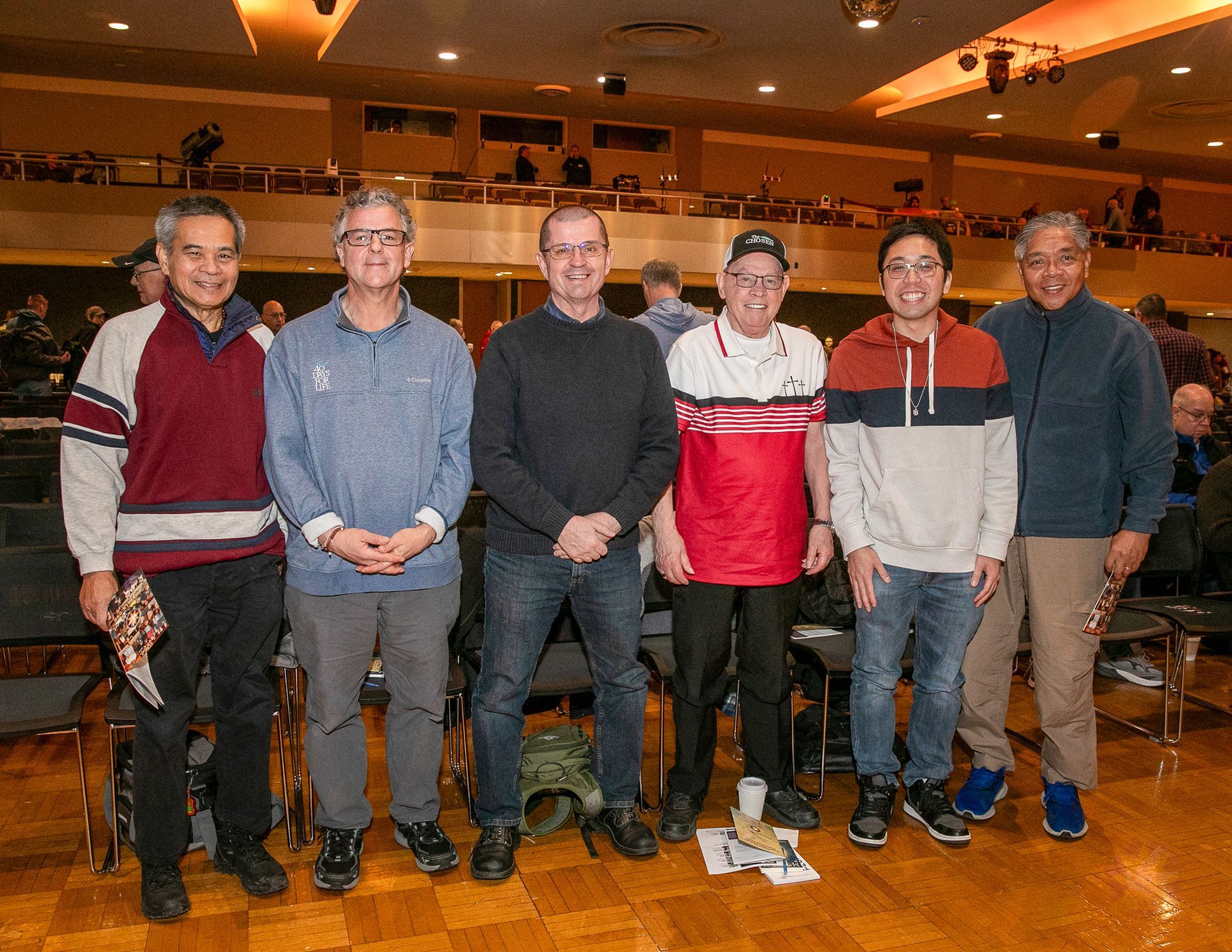 Six people standing in a hall, posing for a group photo.