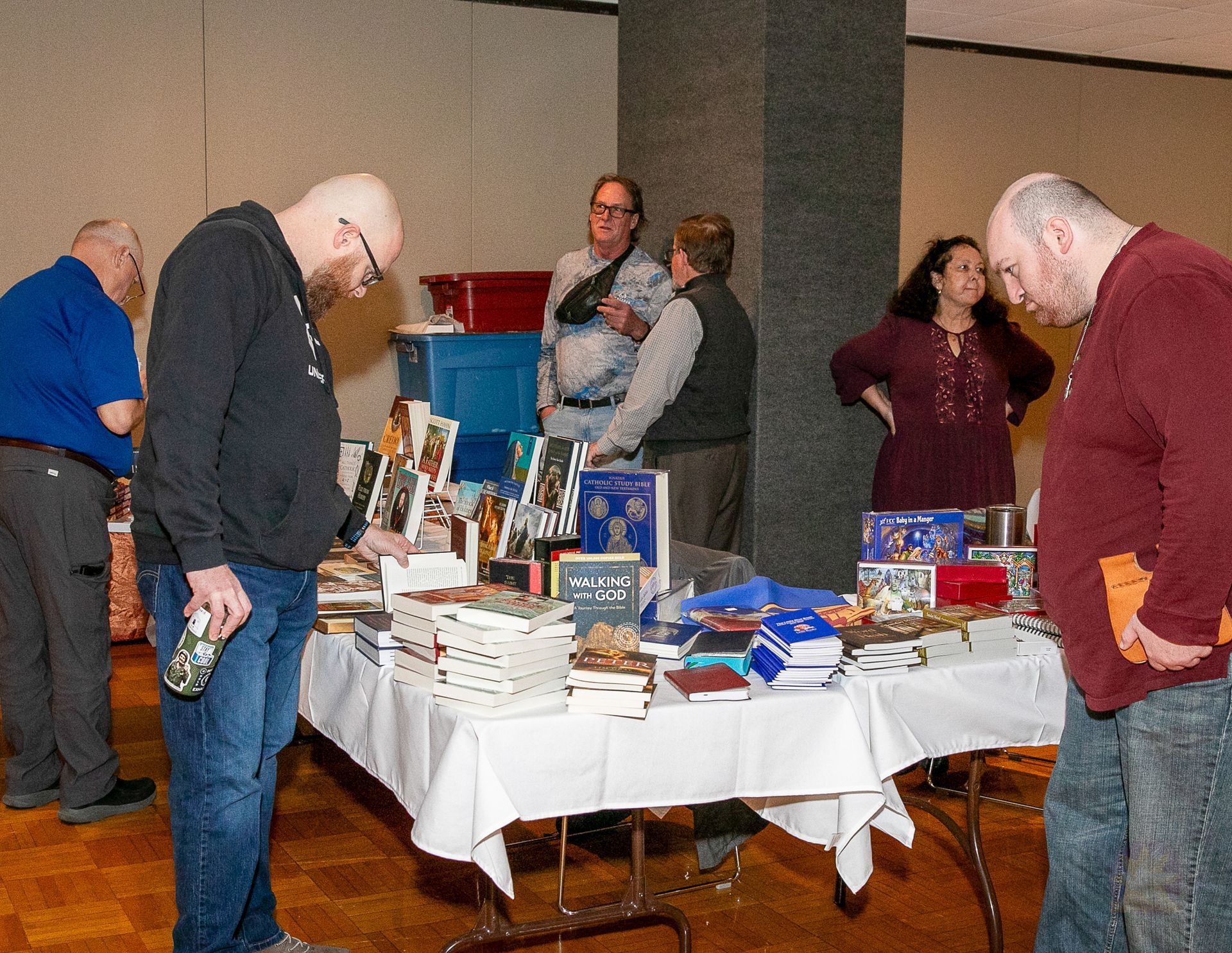 People browsing a table of books and items at an indoor event