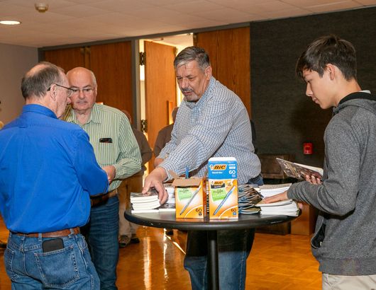 People gathered around a table with brochures at an indoor networking event