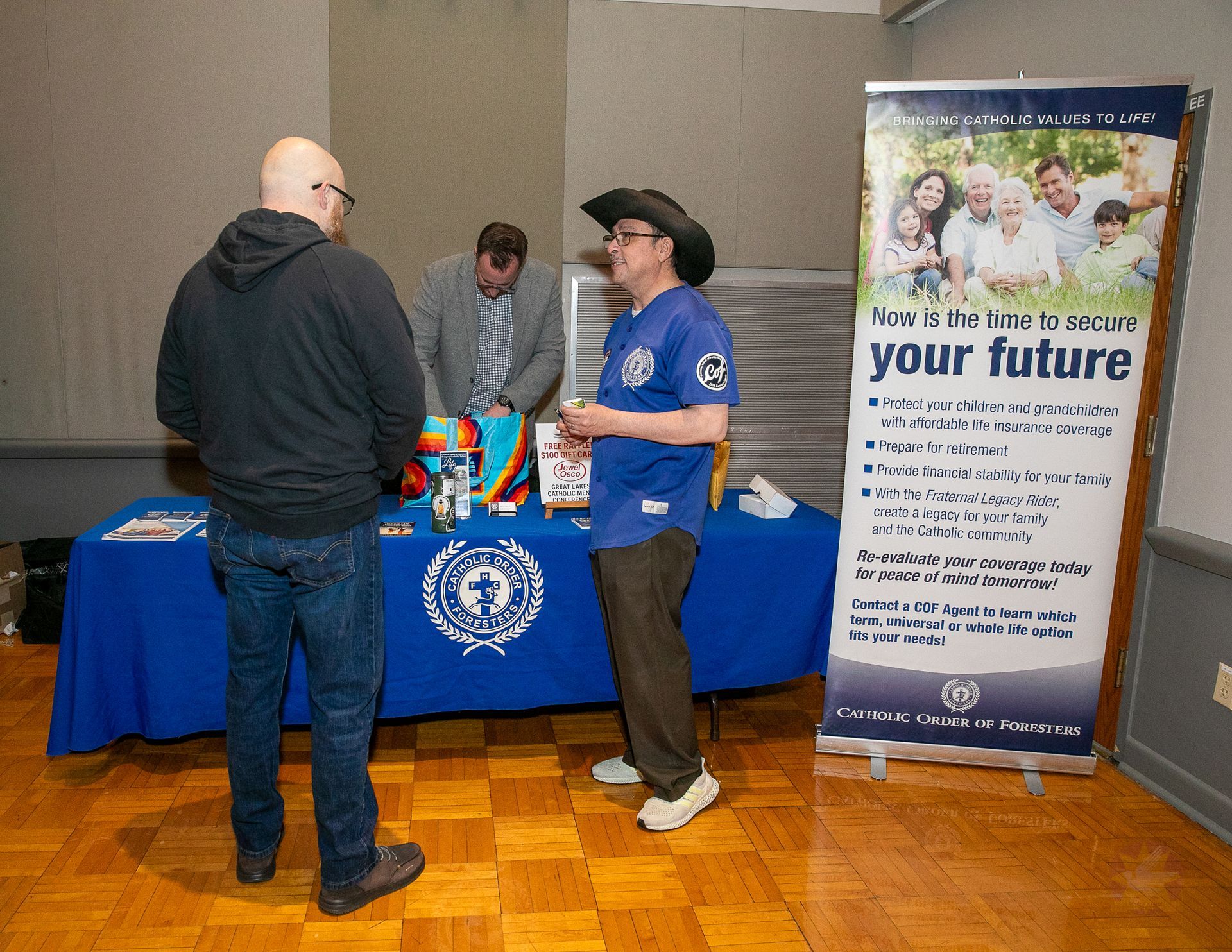 People at a blue table beside a “plan your future” banner at an indoor event.