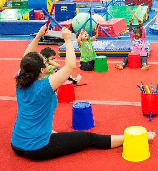A woman in a blue shirt is sitting on the floor playing with children