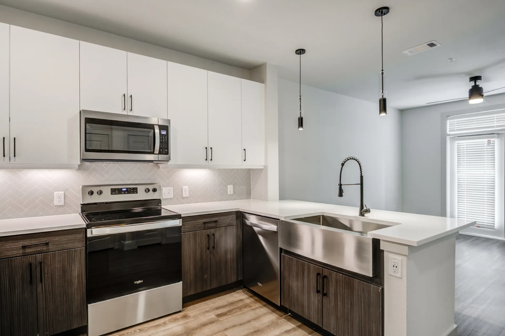Modern kitchen with stainless steel appliances, white cabinets, and a large sink.