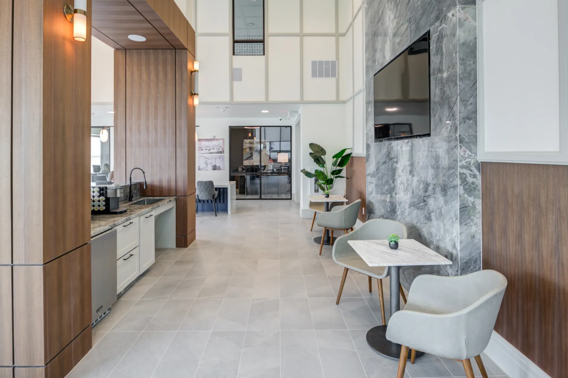 Modern community lounge area with coffee bar, seating, and a TV.