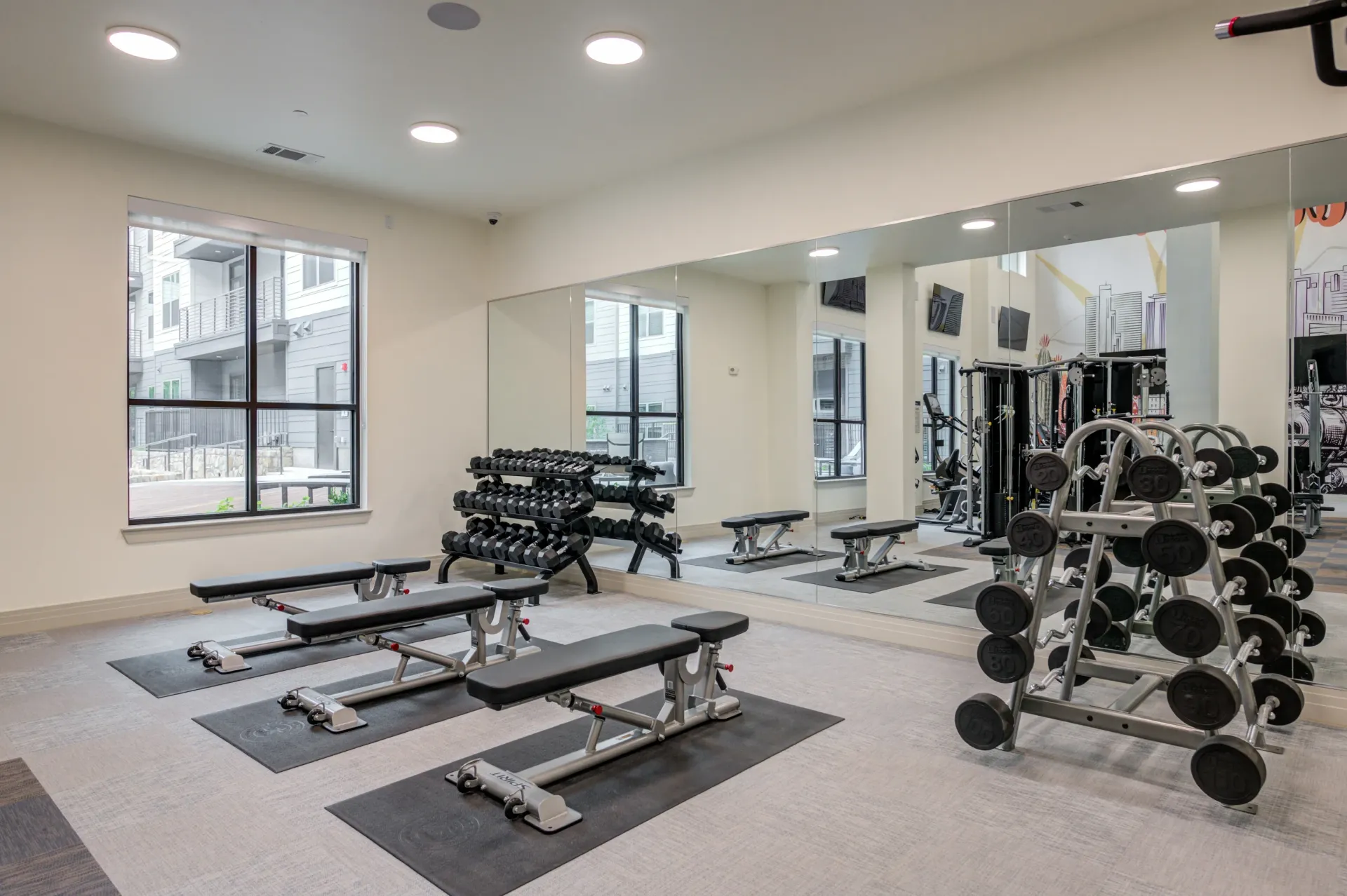 Weight room with dumbbell racks, weight benches, and mirrors.