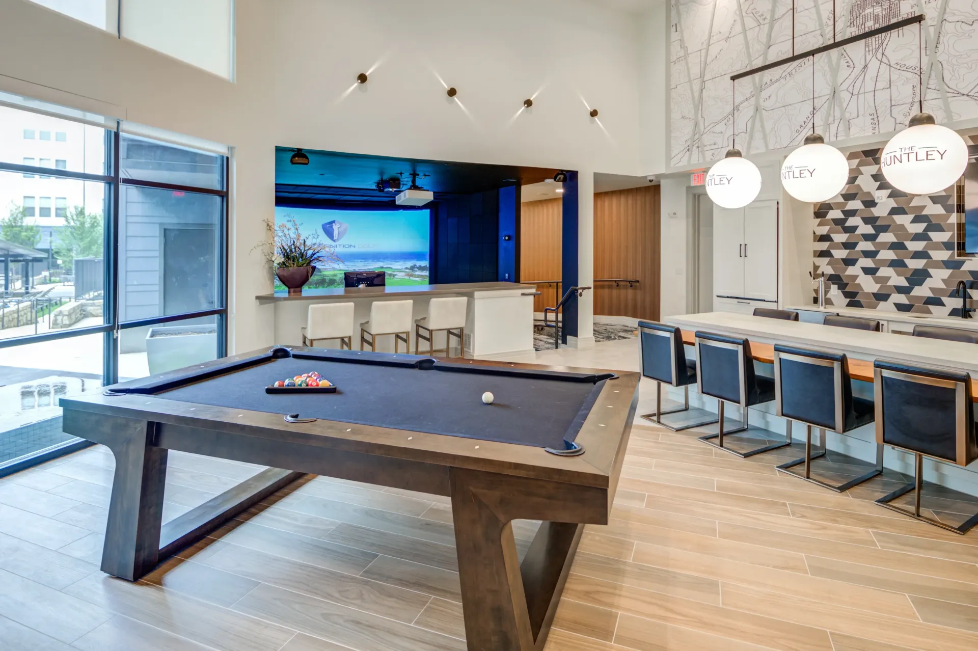 Billiard table and bar area in community lounge with large screen display.