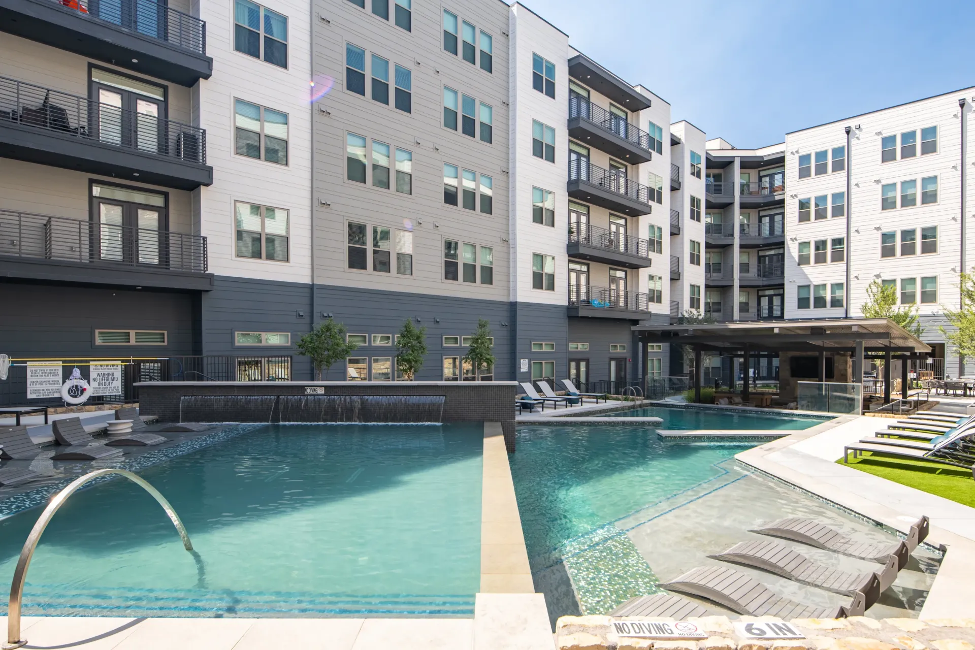 Modern apartment building with a resort-style swimming pool and lounge chairs.