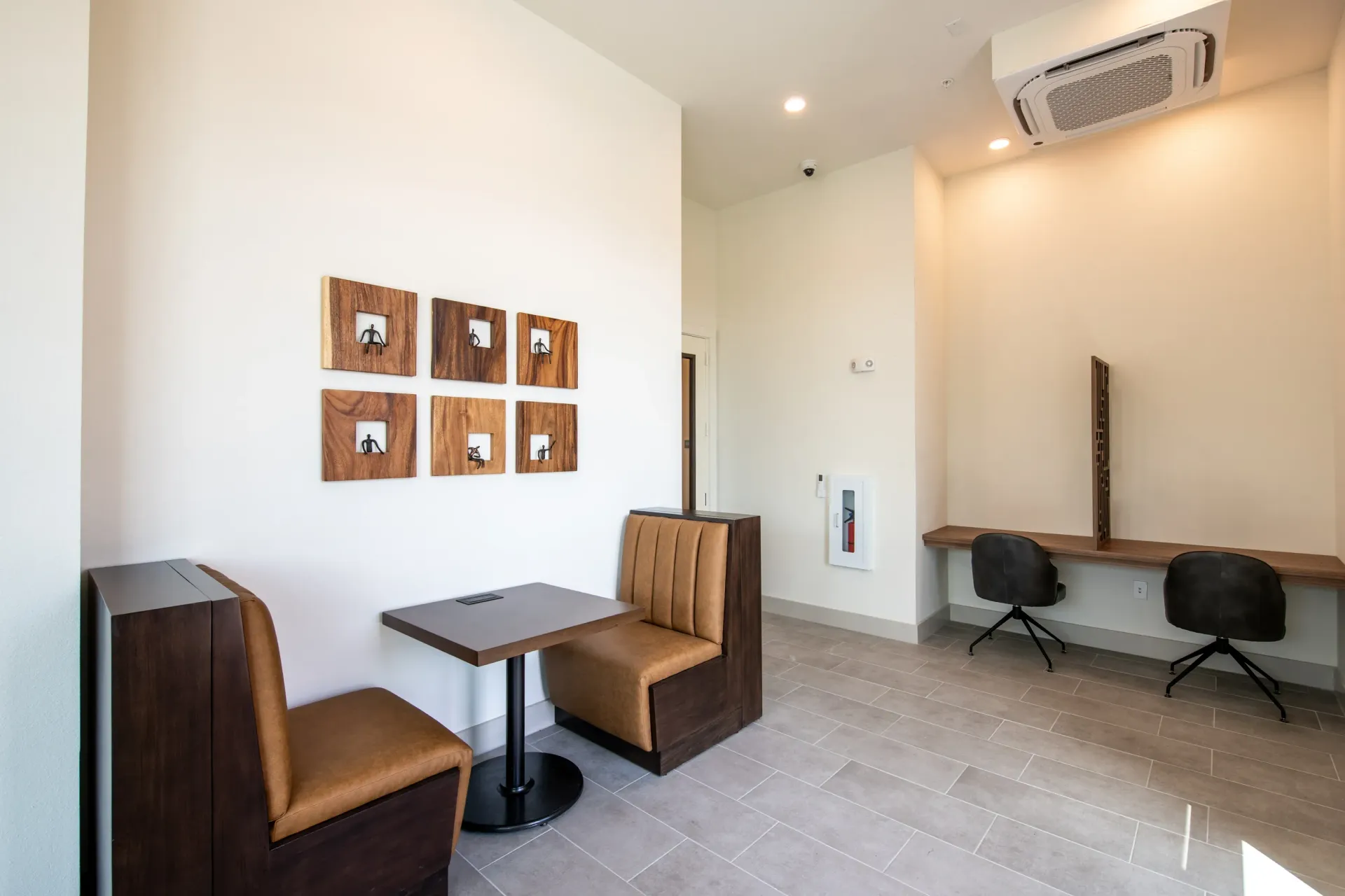 Modern seating area with booths and tables, and a communal work desk with chairs.