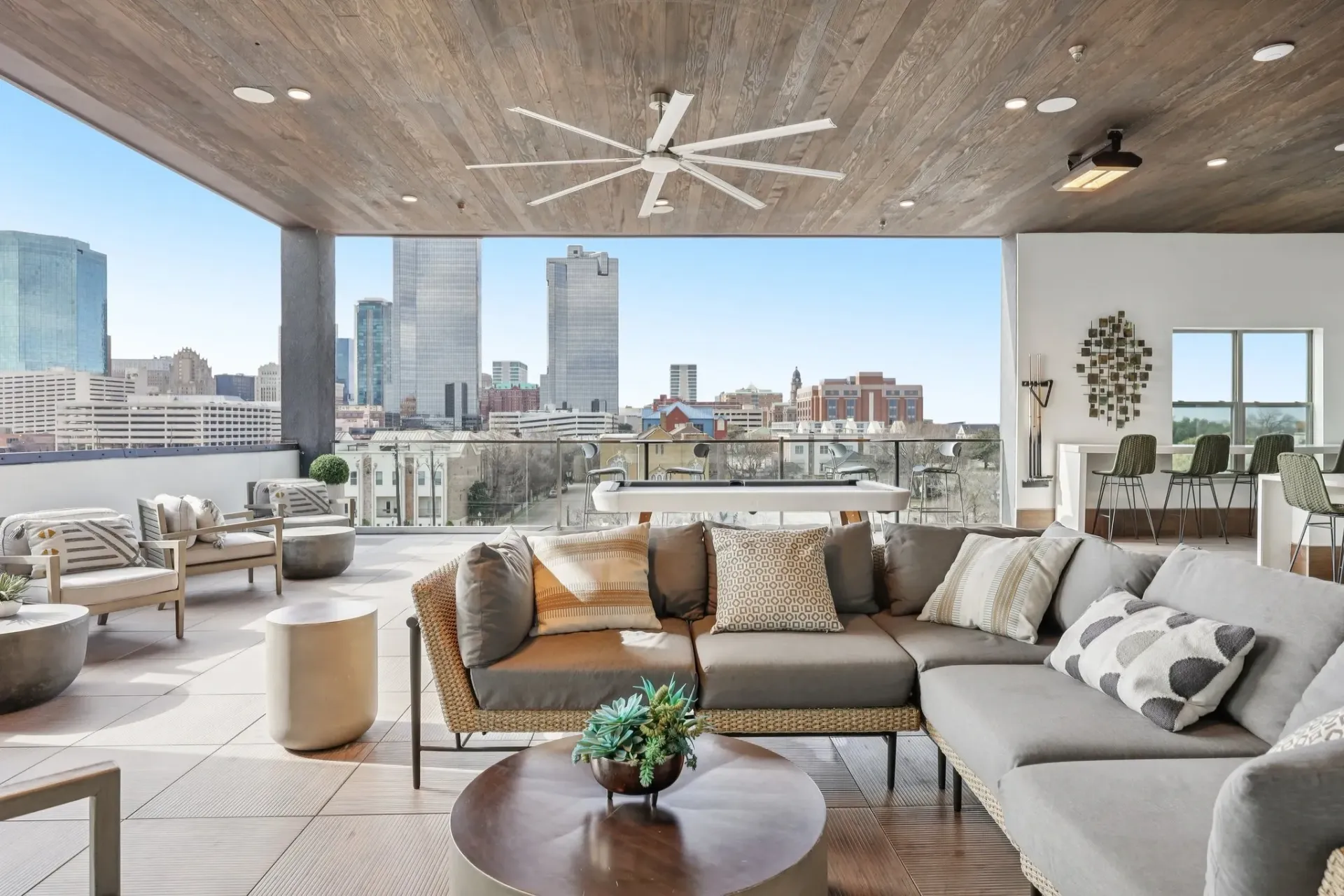 Modern outdoor lounge area with sofas and city skyline view.