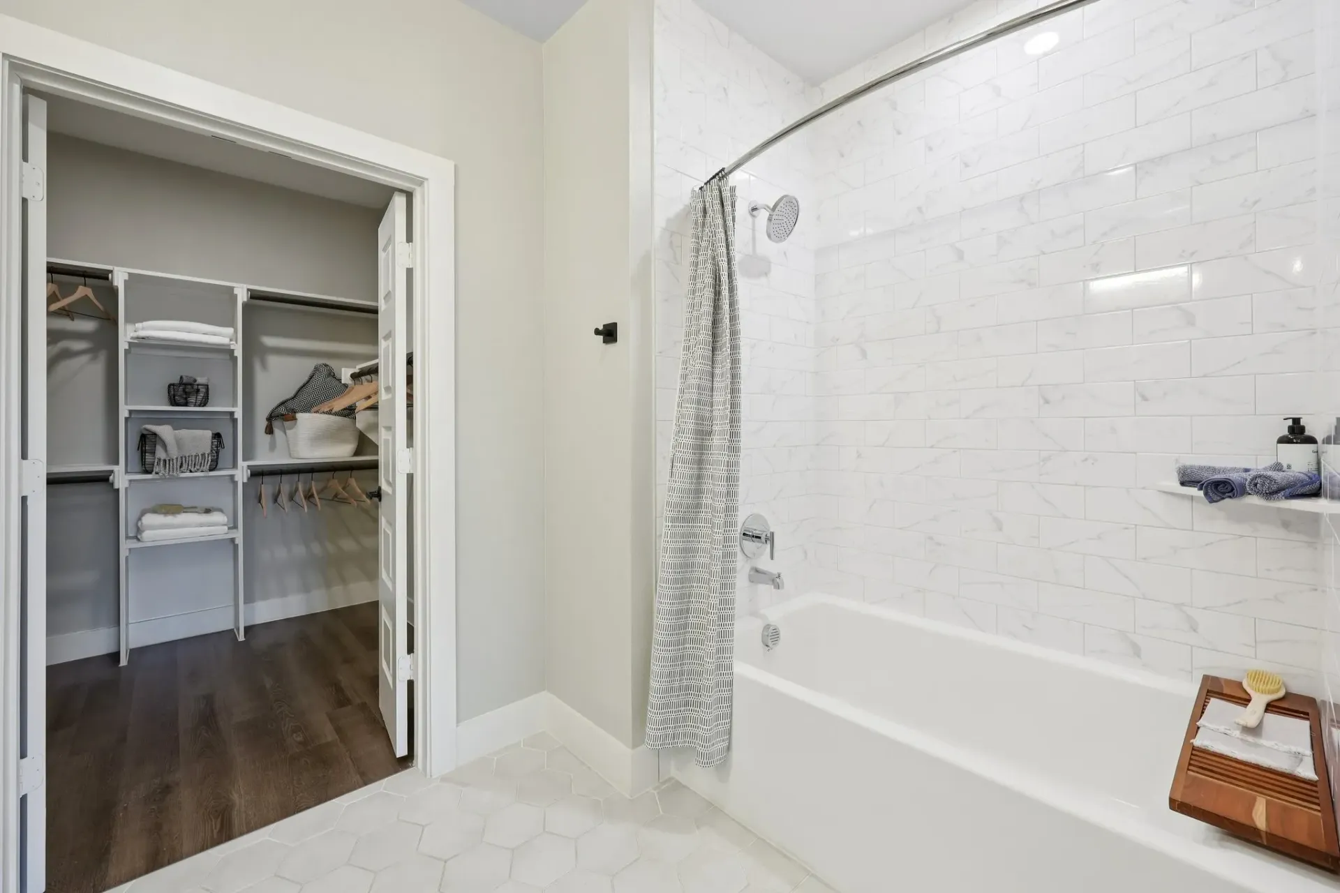 Modern bathroom with a bathtub, shower, and a walk-in closet.