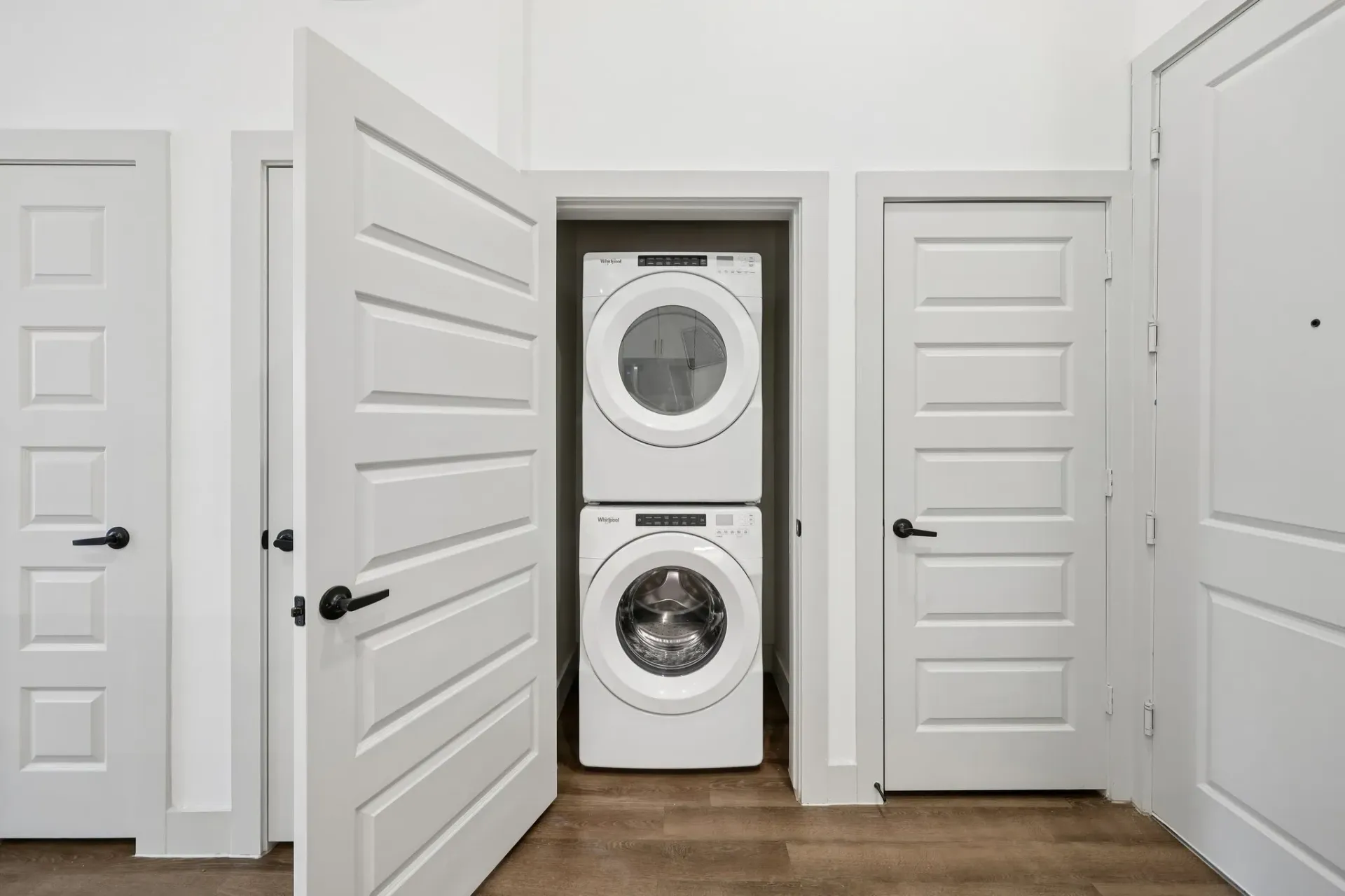 Stacked washer and dryer in a closet with white doors.