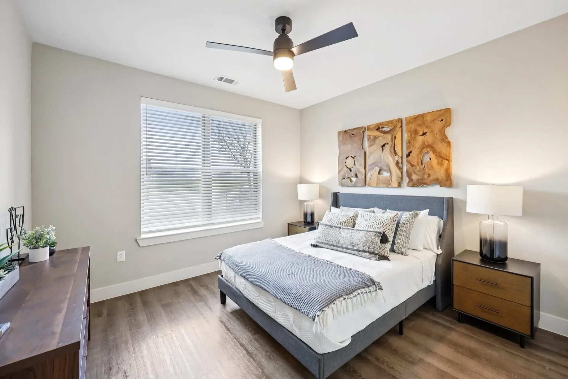 Modern bedroom with a queen-size bed, ceiling fan, and a dresser.