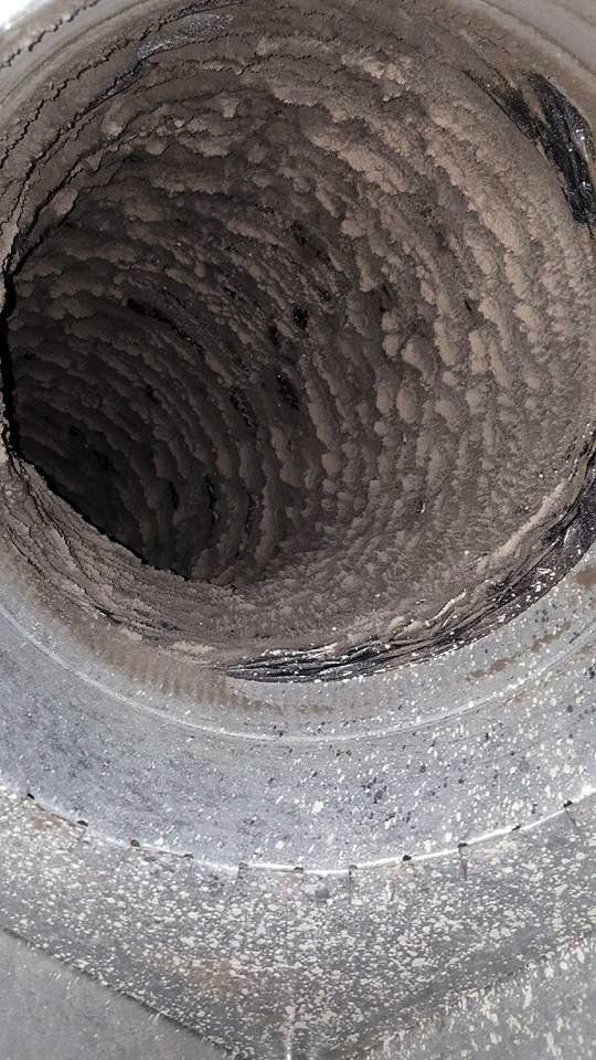 Dirty, circular air duct interior with heavy buildup.