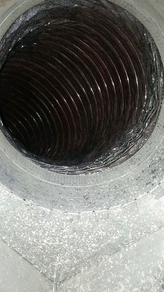 Inside view of dirty, flexible air duct with dark debris coating the interior.