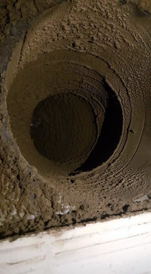 Inside of a dirty air vent covered in layers of dust and debris.