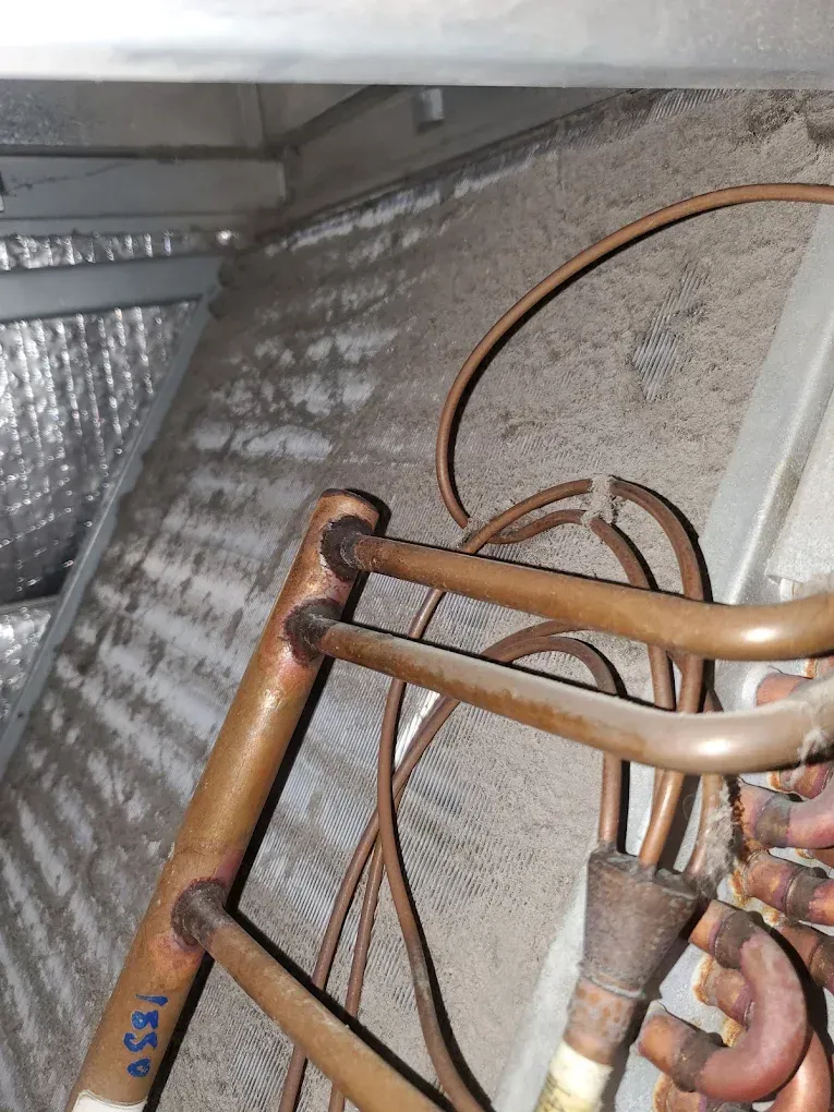 Copper tubes and a dusty air conditioning coil inside a metal frame.