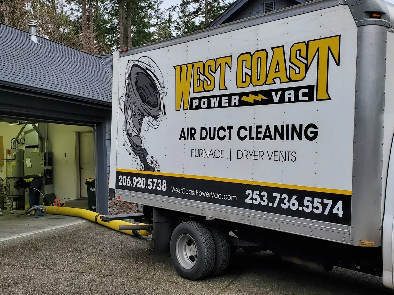 A West Coast Power Vac truck at a garage, with yellow hose extended for air duct cleaning.